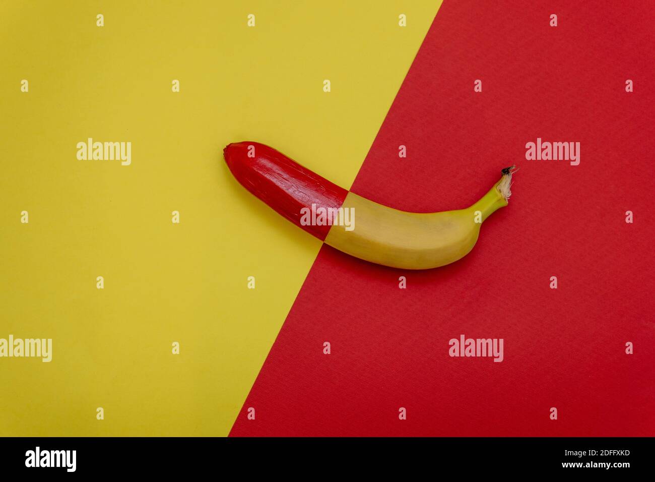 Halbe rote Banane auf zweifarbigem Hintergrund. Flach liegend. Minimales Lebensmittelkonzept Stockfoto