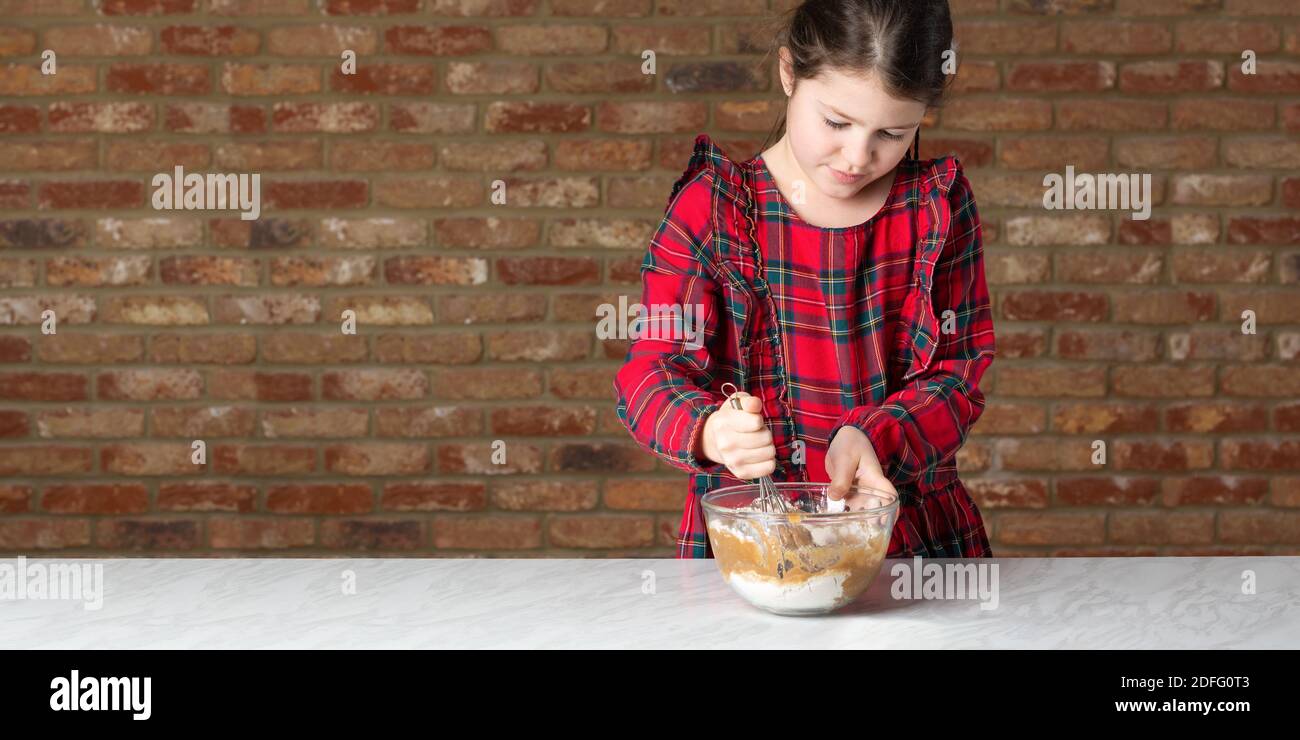 Kleines Mädchen in roten Tartan Kleid Mischen Teig Stockfoto