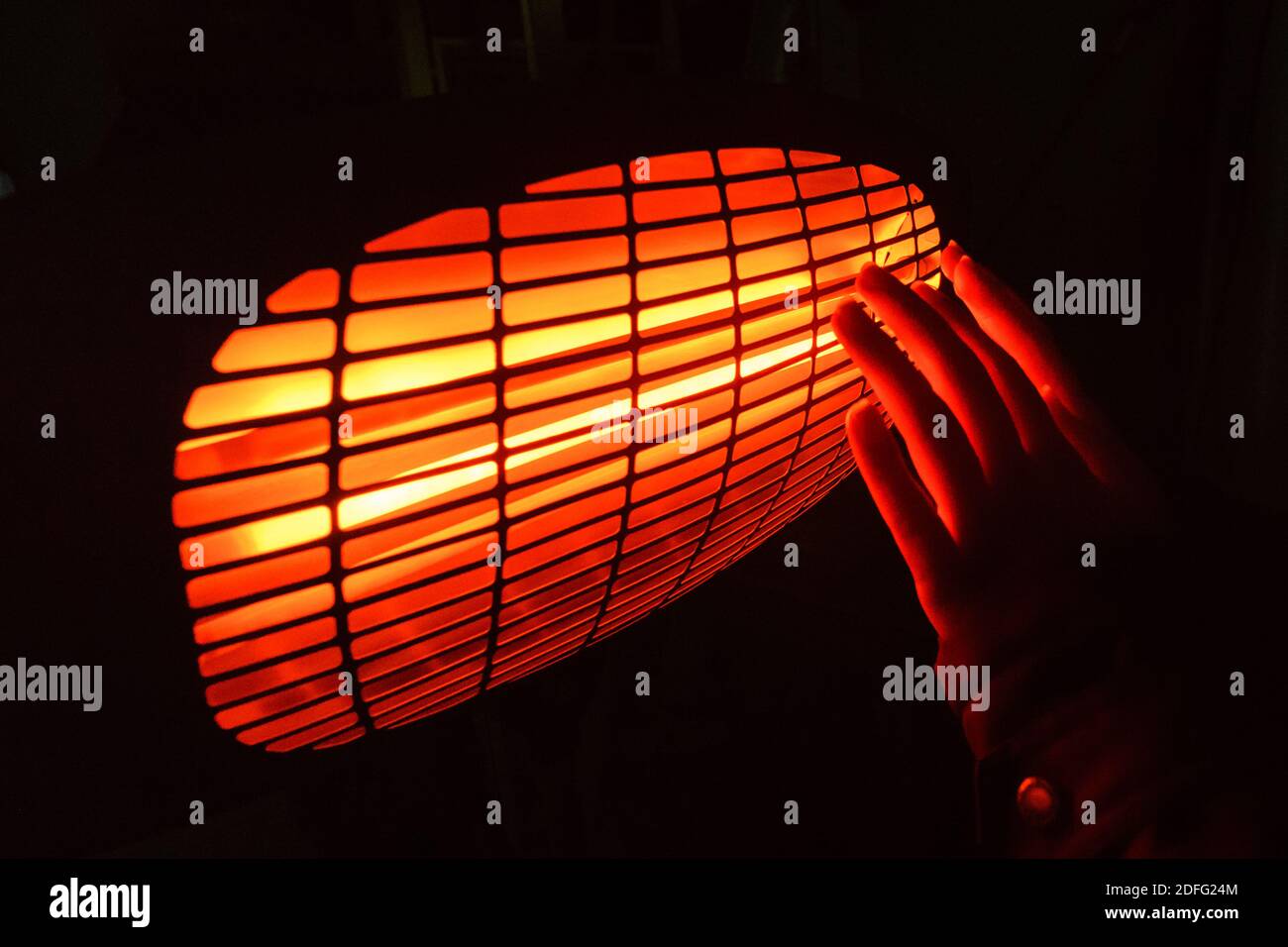 Infrarot-Heizung wärmt die Hände im Dunkeln Stockfoto