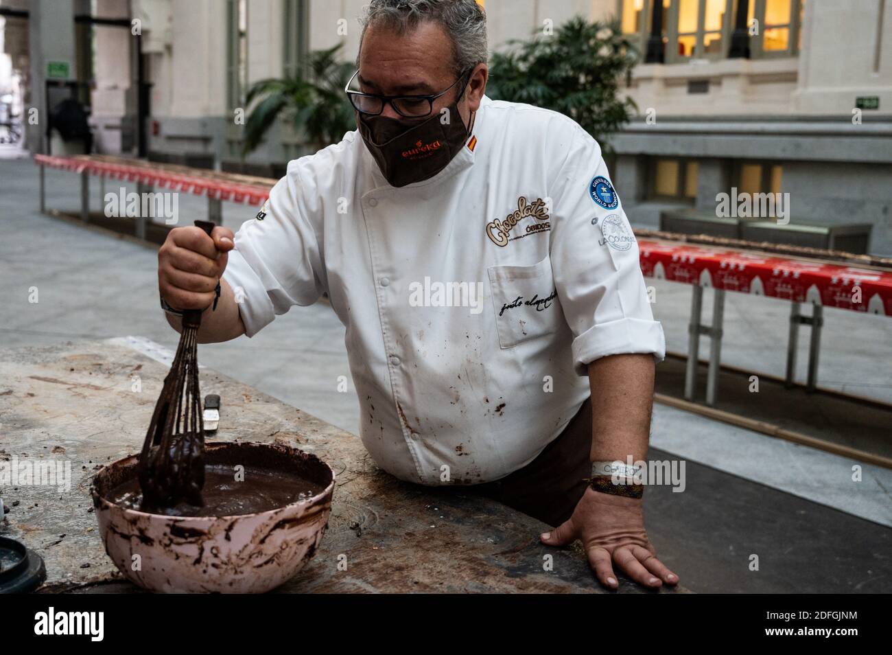 Der Meister Chocolatier Justo Almendrote, von Spaniens ältester Schokoladenfabrik La Colonial, rührt Schokolade, um den weltweit größten Schokoladenmandelnougat, auf Spanisch bekannt als "Turron", mit 50 Meter Länge (164 Fuß) zu machen. Zweihundert Kilo Schokolade, 100 Liter Sahne, 90 Kilo Mandeln und 9 Stunden für die Herstellung, die in Tausende von Tabletten geschnitten werden, werden an die Öffentlichkeit verkauft und der Erlös wird für soziale Zwecke der Fundacion Esperanza y Alegria verwendet. "Turron" ist eine typische Weihnachtssüße, die in Spanien sehr konsumiert wird. Stockfoto