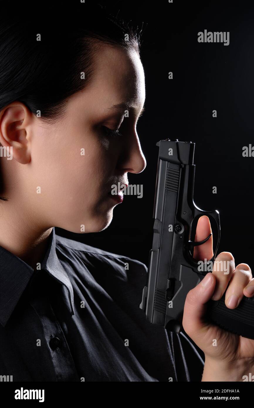 Weibliche Porträt mit Pistole Nahaufnahme auf schwarzem Hintergrund Seitenansicht Stockfoto