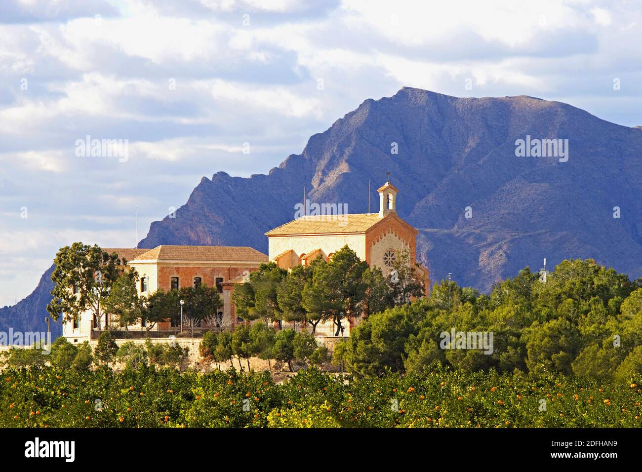 In der Nähe von Algorfa, im Landesinneren an der Costa Blanca, liegt Spanien die 'Ermita de la Virgen del Carmen' umgeben von Orangenbäumen mit dem Callosa-Berg dahinter. Stockfoto