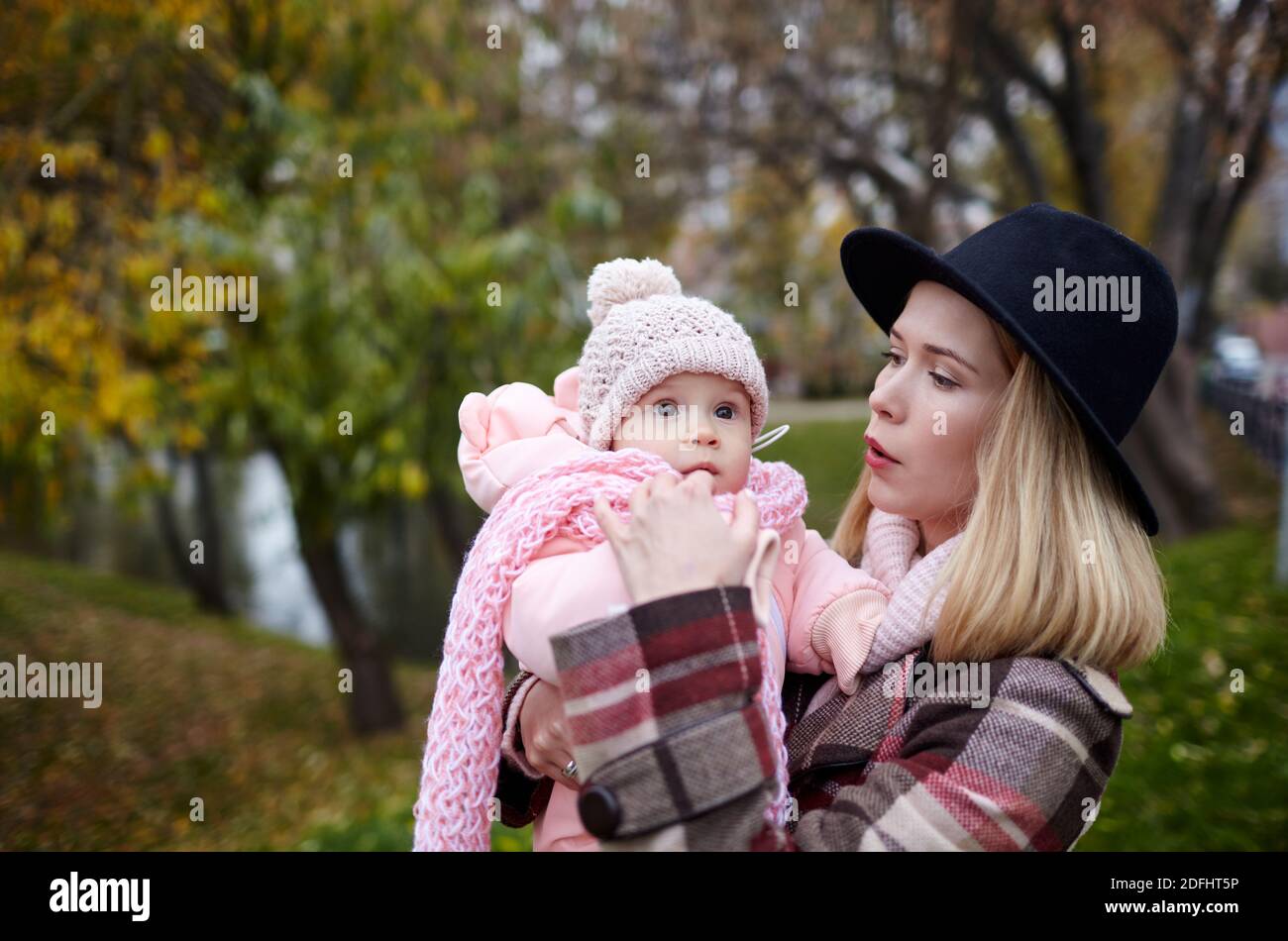 Schöne Baby-Mädchen mit Mutter im Freien. Familien im Freien. Liebenswert kleines Mädchen in warmen Kleidern im Herbst Park an sonnigen Tag. Stockfoto
