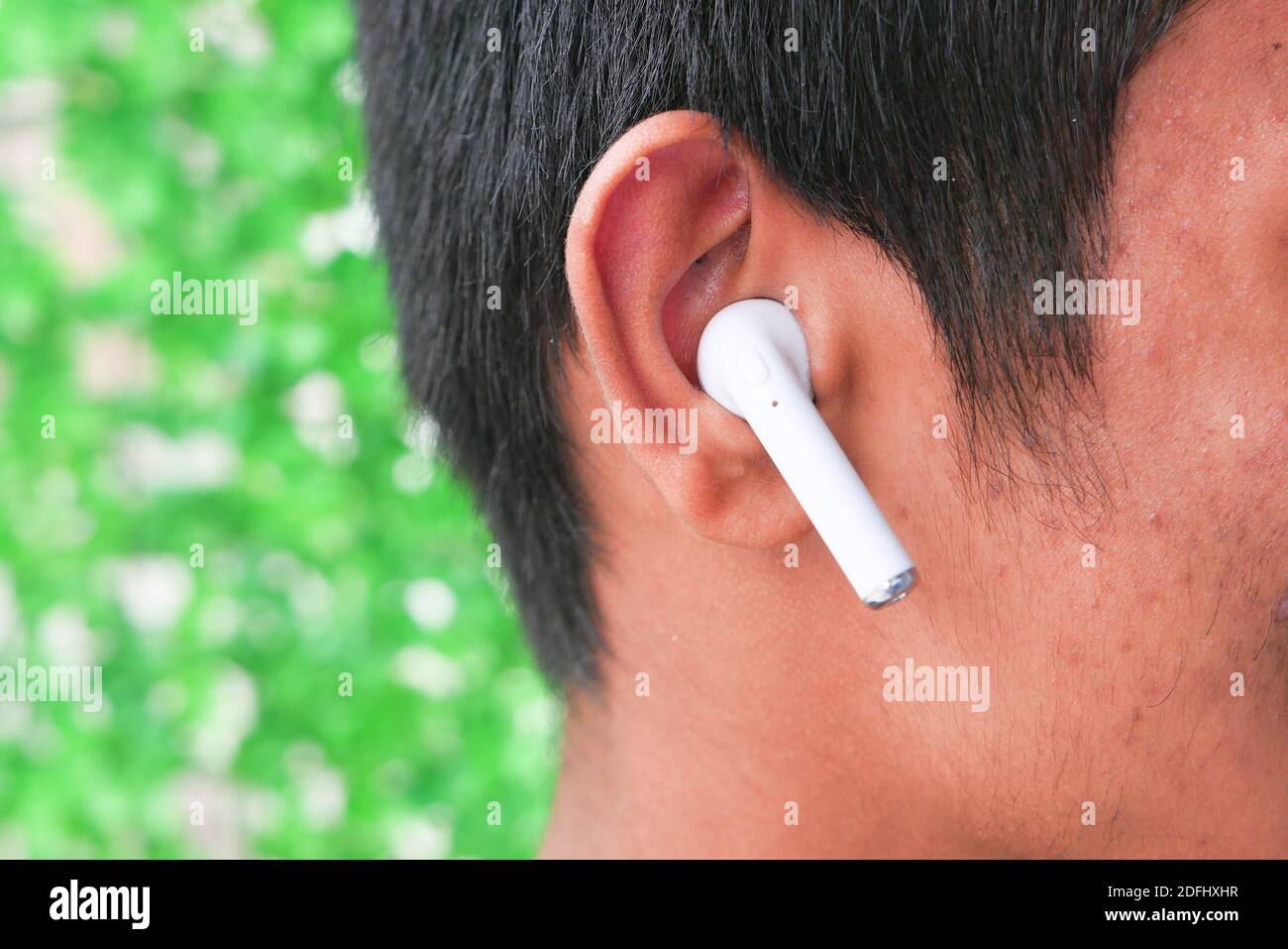 Junger Mann, der schnurloses Telefon aus nächster Nähe hören kann Stockfoto
