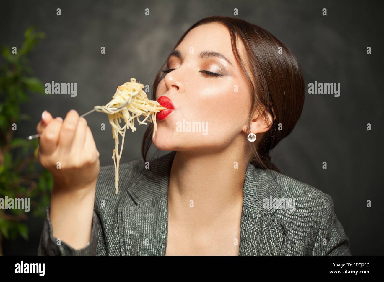 Glückliche Frau essen italienische Pasta Spaghetti auf schwarzem Hintergrund Stockfoto