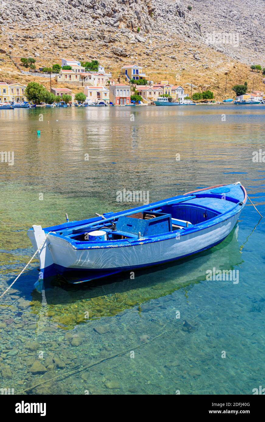 Kleines blaues Holzboot in den ruhigen Gewässern der Pedi Bay, Symi Island, Dodekanes, Griechenland Stockfoto