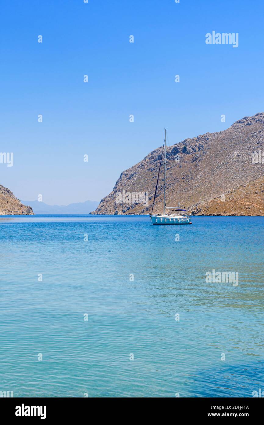 Yacht vor Anker in den ruhigen Gewässern der Pedi Bay, Symi Island, Dodekanes, Griechenland Stockfoto
