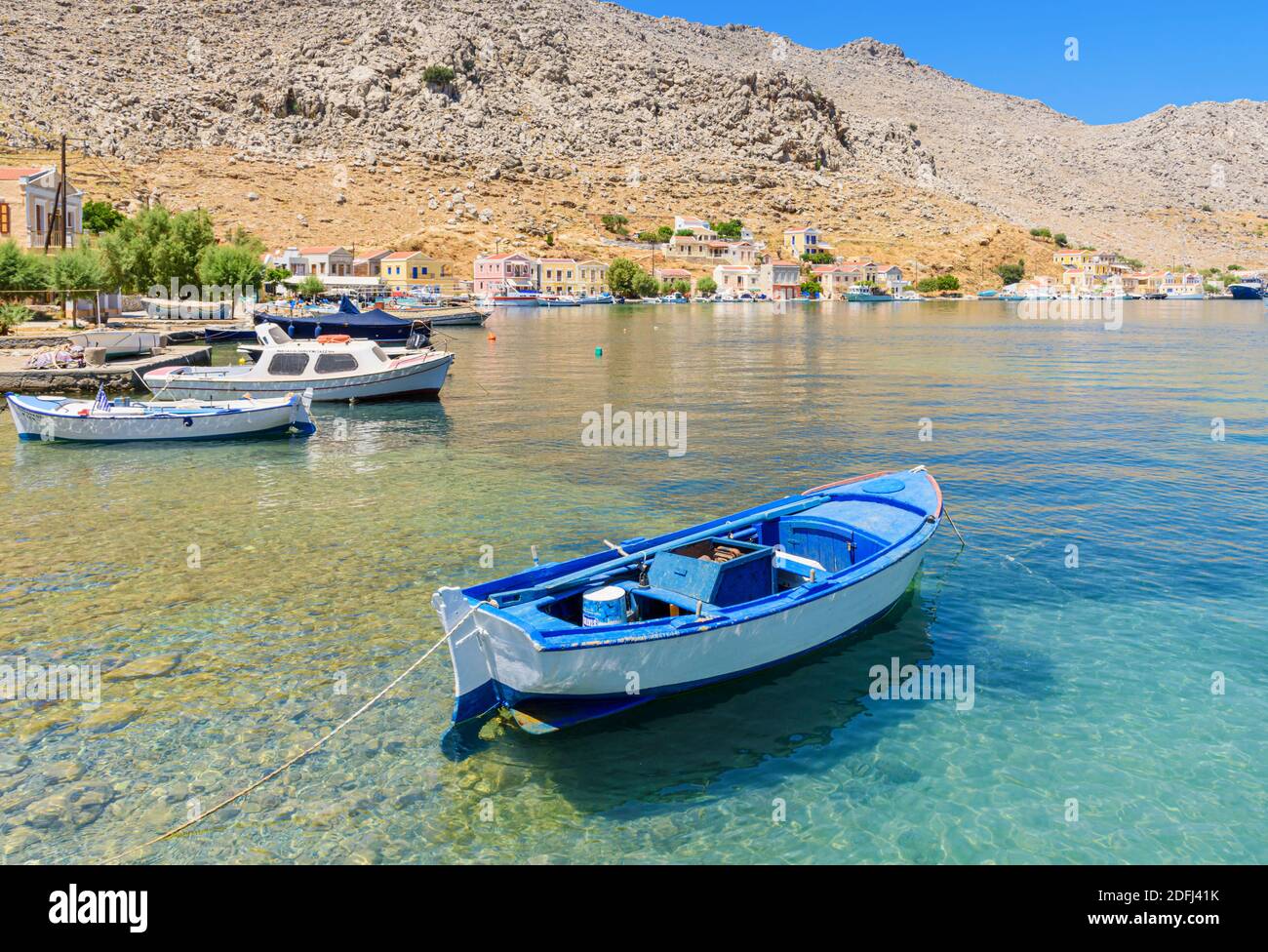 Kleines blaues Holzboot in den ruhigen Gewässern der Pedi Bay, Symi Island, Dodekanes, Griechenland Stockfoto