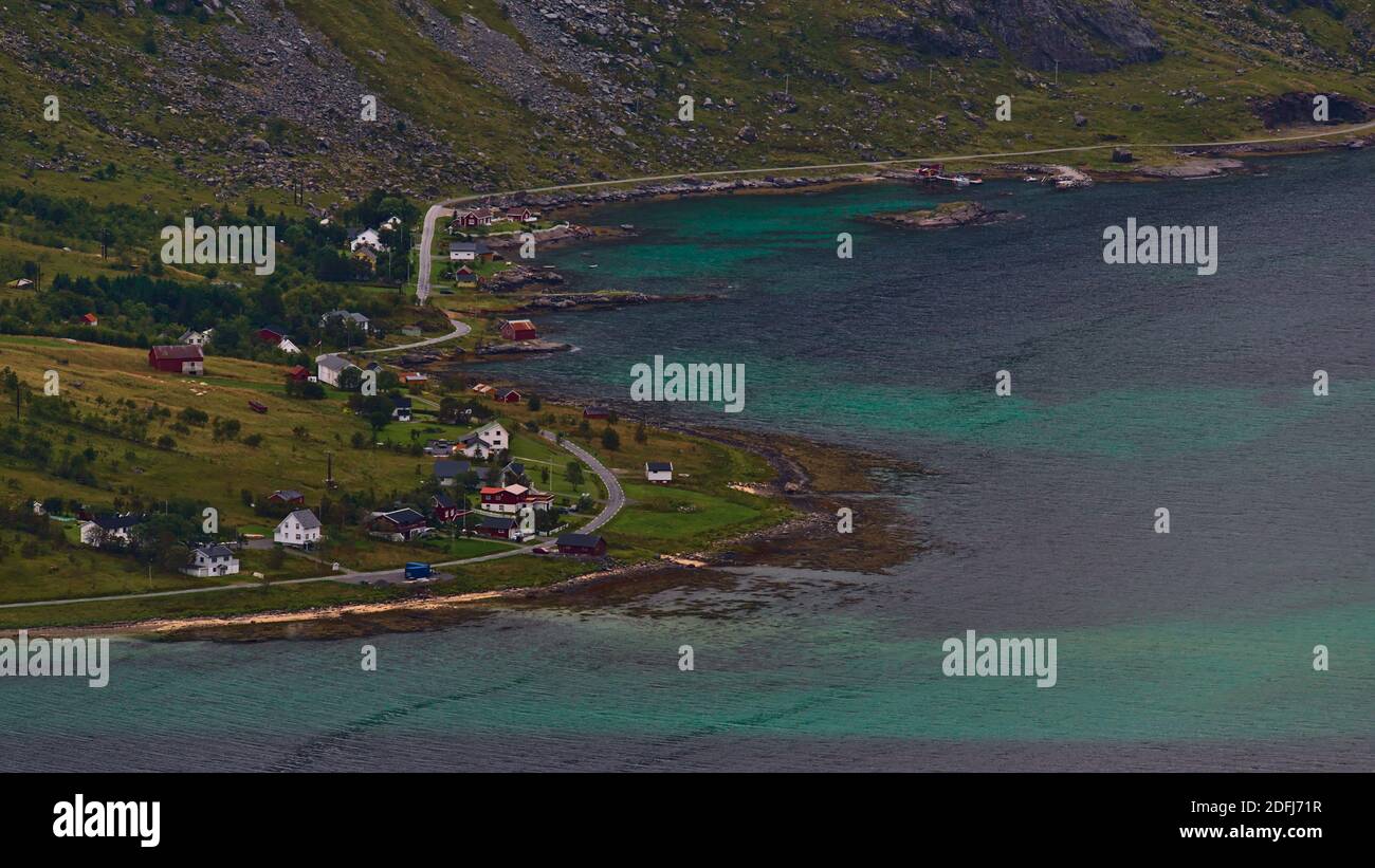 Atemberaubende Luftaufnahme eines kleinen Dorfes am Ufer des Fjords Skjelfjorden auf der Insel Moskenesøya, Lofoten, Norwegen mit traditionellen Holzhäusern. Stockfoto