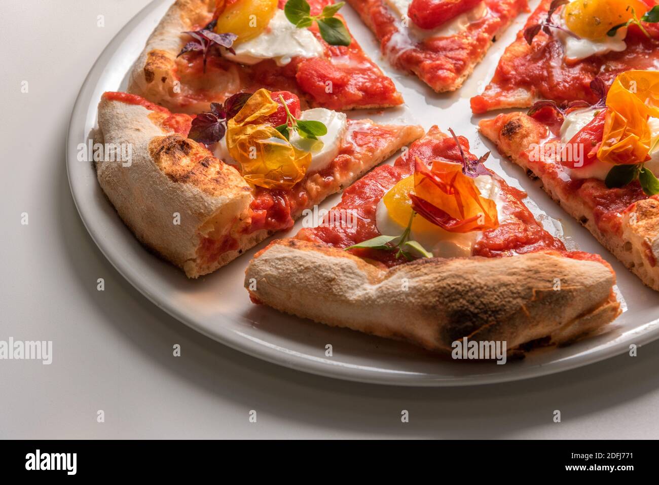 Nahaufnahme von Gourmet-Pizzascheiben mit Tomate, Mozzarella, Basilikum und knackiger Pfefferhaut. Verzehrfertige Pizza Stockfoto