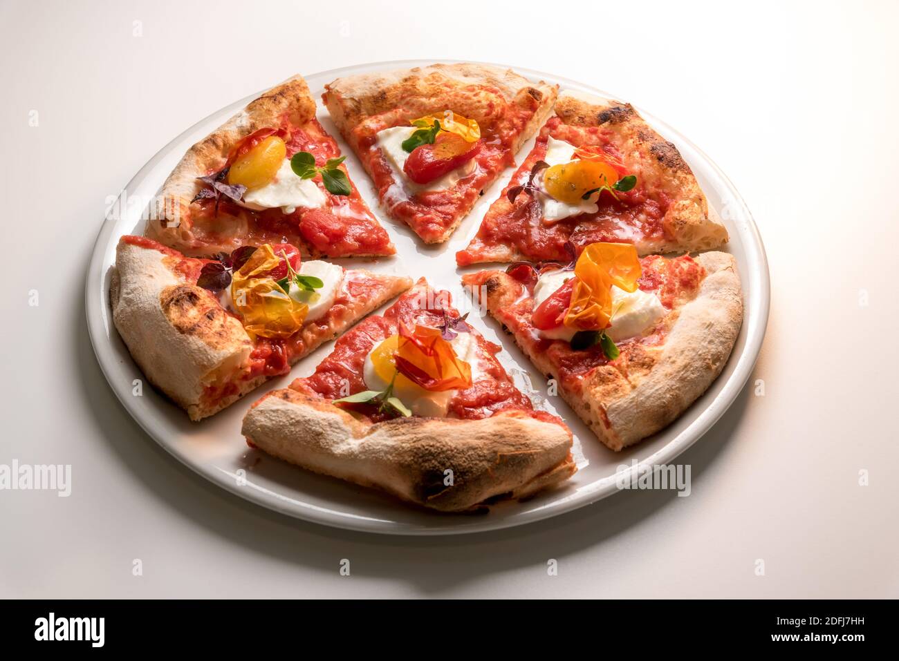 Gourmet-Pizza, eine appetitliche Neuinterpretation der klassischen Neapel-Pizza mit Tomaten, Mozzarella, Basilikum und knuspriger Pfefferhaut. Sechs Scheiben auf der pl Stockfoto