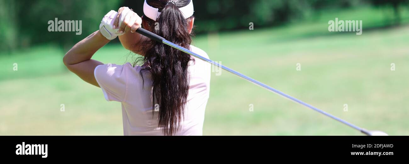 Frau in Anzug halten Golfschläger hinter ihrem Rücken. Stockfoto