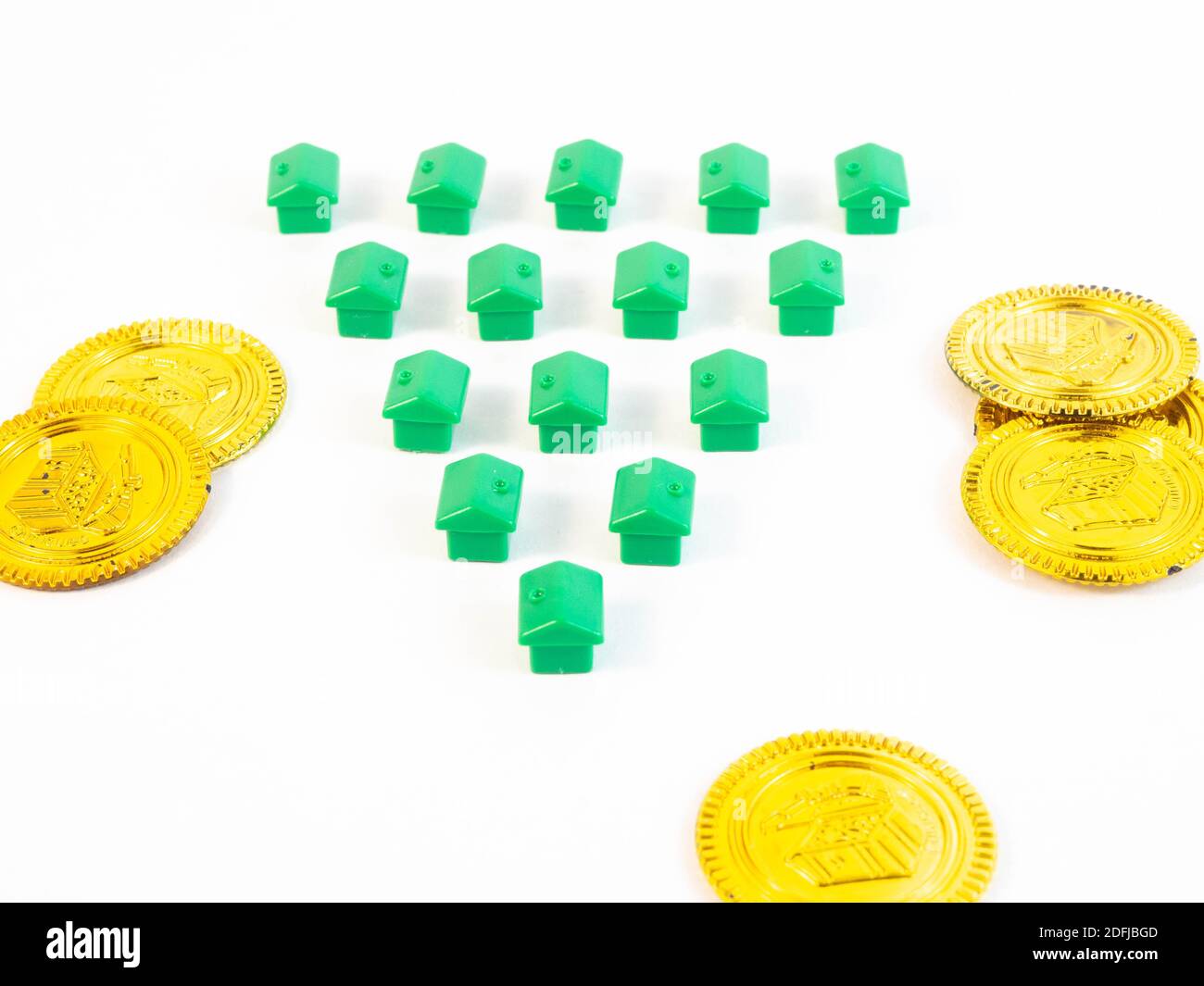 Grün gefärbte Bauern in Form eines Hauses mit Goldmünzen. Konzept rund um Wohnen und Immobilienmakler. Stockfoto