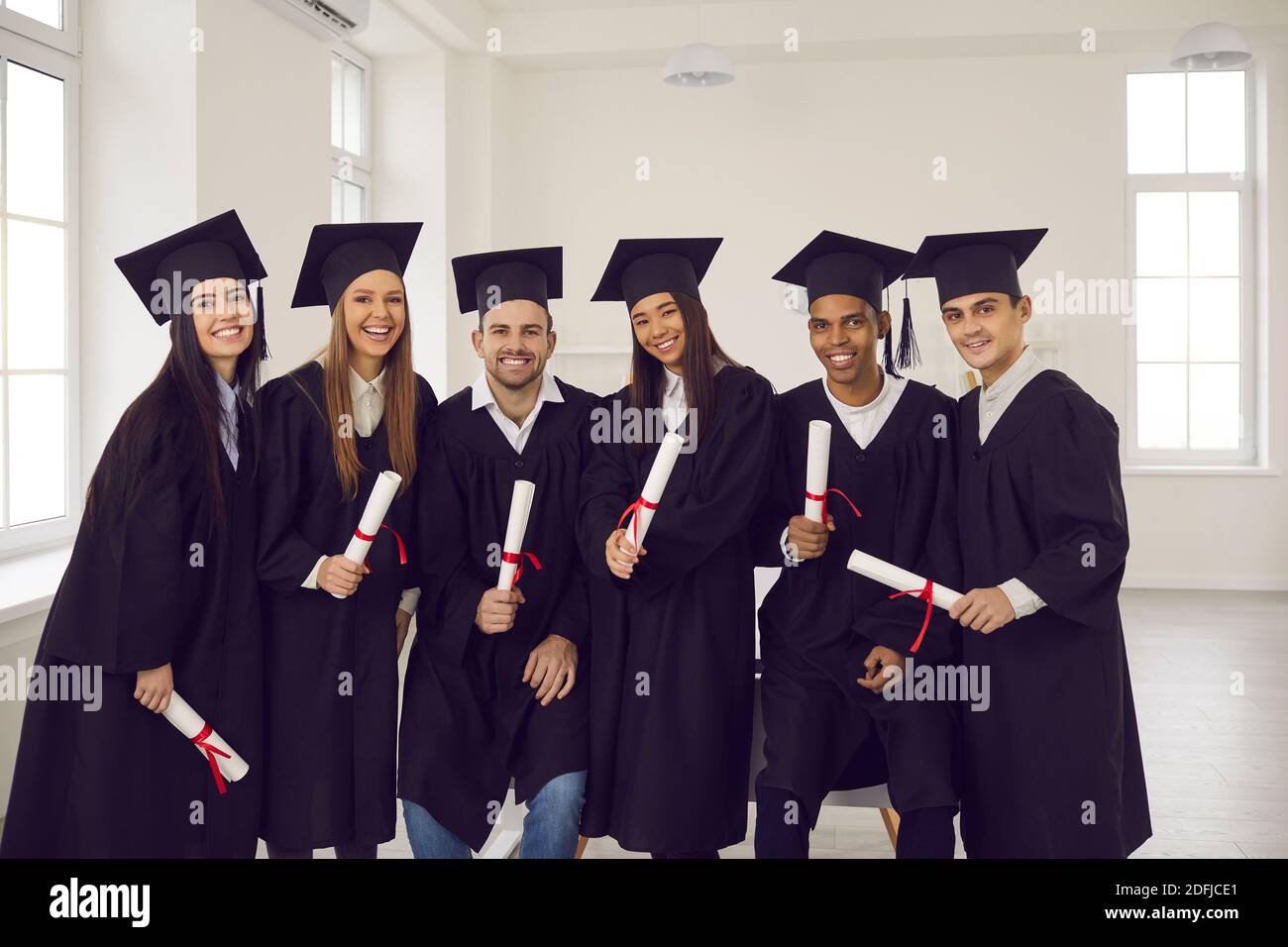 Gruppe von jungen glücklich Hochschulabsolventen multiethnischen Freunden mit Diplomen In Händen Stockfoto