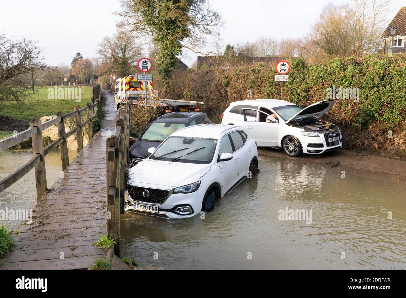 Ein Bergefahrzeug bereitet sich darauf vor, gestrandete überflutete Fahrzeuge an der ford in Much Hadham abzuschleppen. Hertfordshire Großbritannien. Dezember 2020 Stockfoto