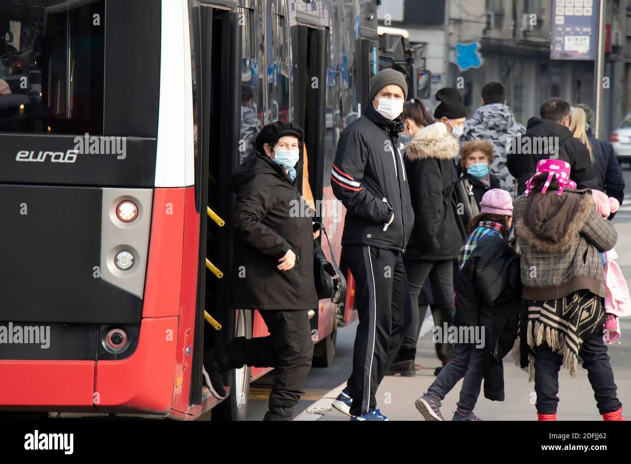 Belgrad, Serbien - 2. Dezember 2020: Menschen mit chirurgischen Gesichtsmasken beim Aussteigen aus einem öffentlichen Bus an einer Bushaltestelle der Stadt , im Winter Stockfoto