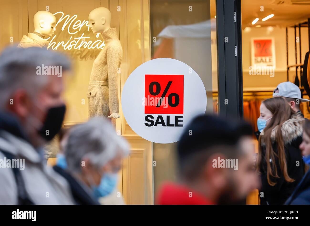 Essen, Ruhrgebiet, Nordrhein-Westfalen, Deutschland - Schaufenster eines Modehauses zur Weihnachtszeit mit Sonderangeboten, Passanten mit Schutzfolie Stockfoto