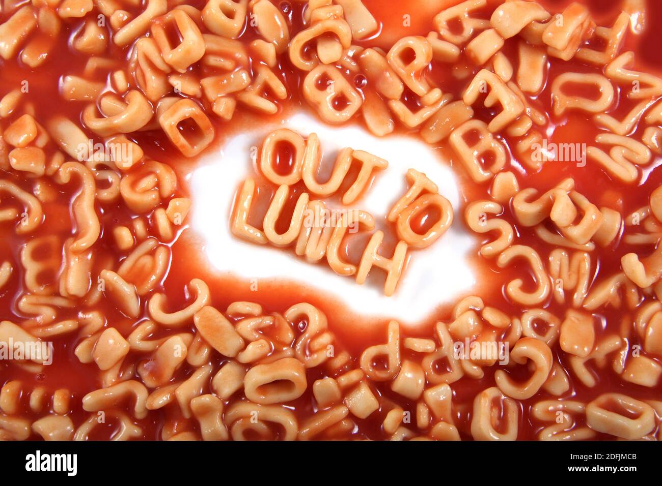 Das Wort ‘out to Lunch’ in Alphabettispaghetti, orangen Pastabuchstaben geschrieben. Stockfoto