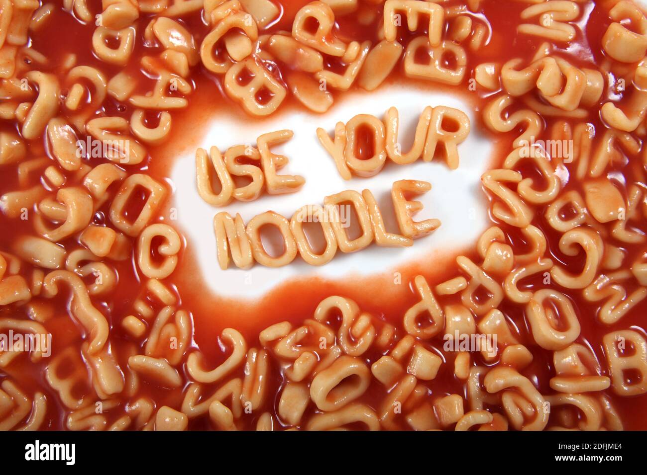Die Worte ‘use your noodle’ geschrieben in Alphabeti Spaghetti, orange Pasta-förmigen Buchstaben. Stockfoto