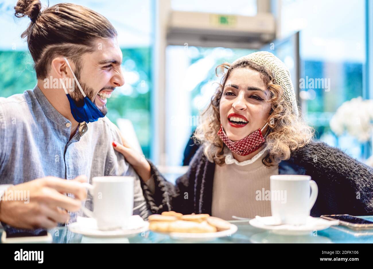 Glückliches Paar trägt Gesichtsmaske Spaß zusammen an der Bar Cafeteria - Neue normale Lifestyle-Konzept mit jungen Menschen auf Positive Stimmung Stockfoto