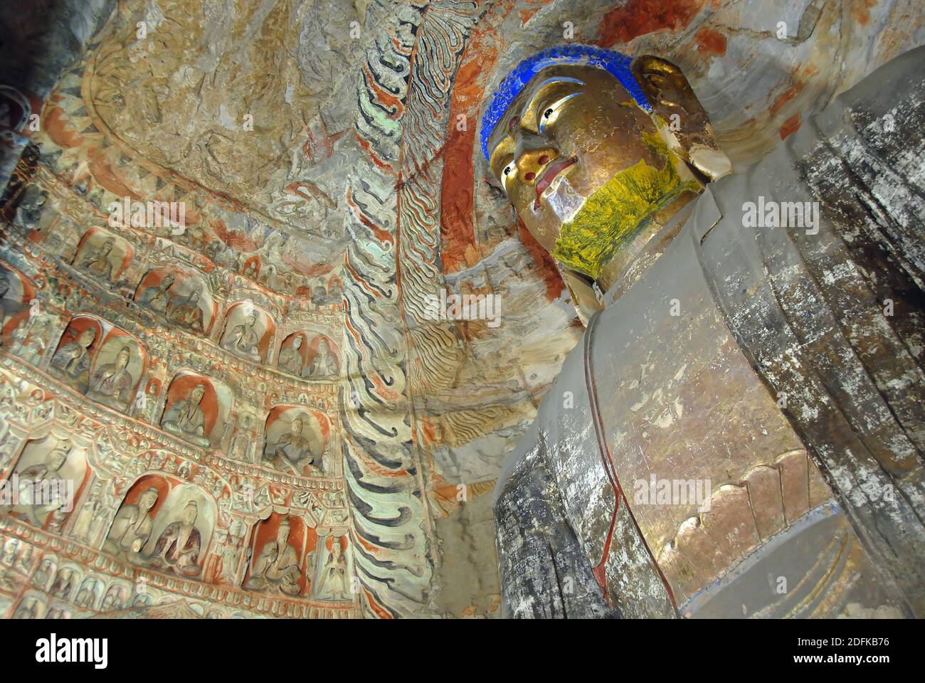 Yungang Grotten in der Nähe von Datong in der Provinz Shanxi, China. Große alte Statue von Buddha in einer Höhle bei Yungang mit goldenem Gesicht und blauem Haar. Stockfoto