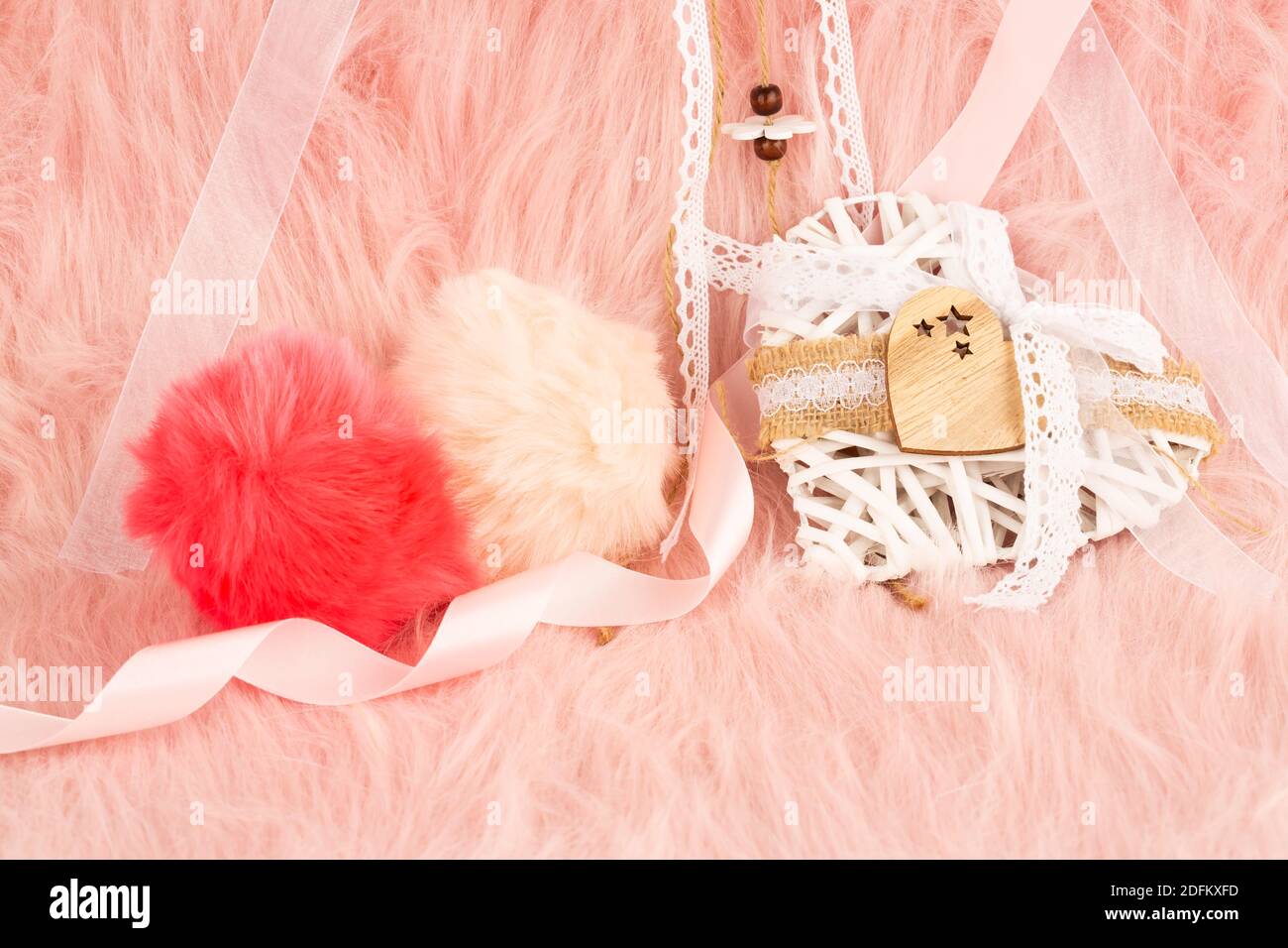 Weiße hölzerne Herz mit Schleife und flauschige Kugeln auf Pelz Hintergrund. Stockfoto