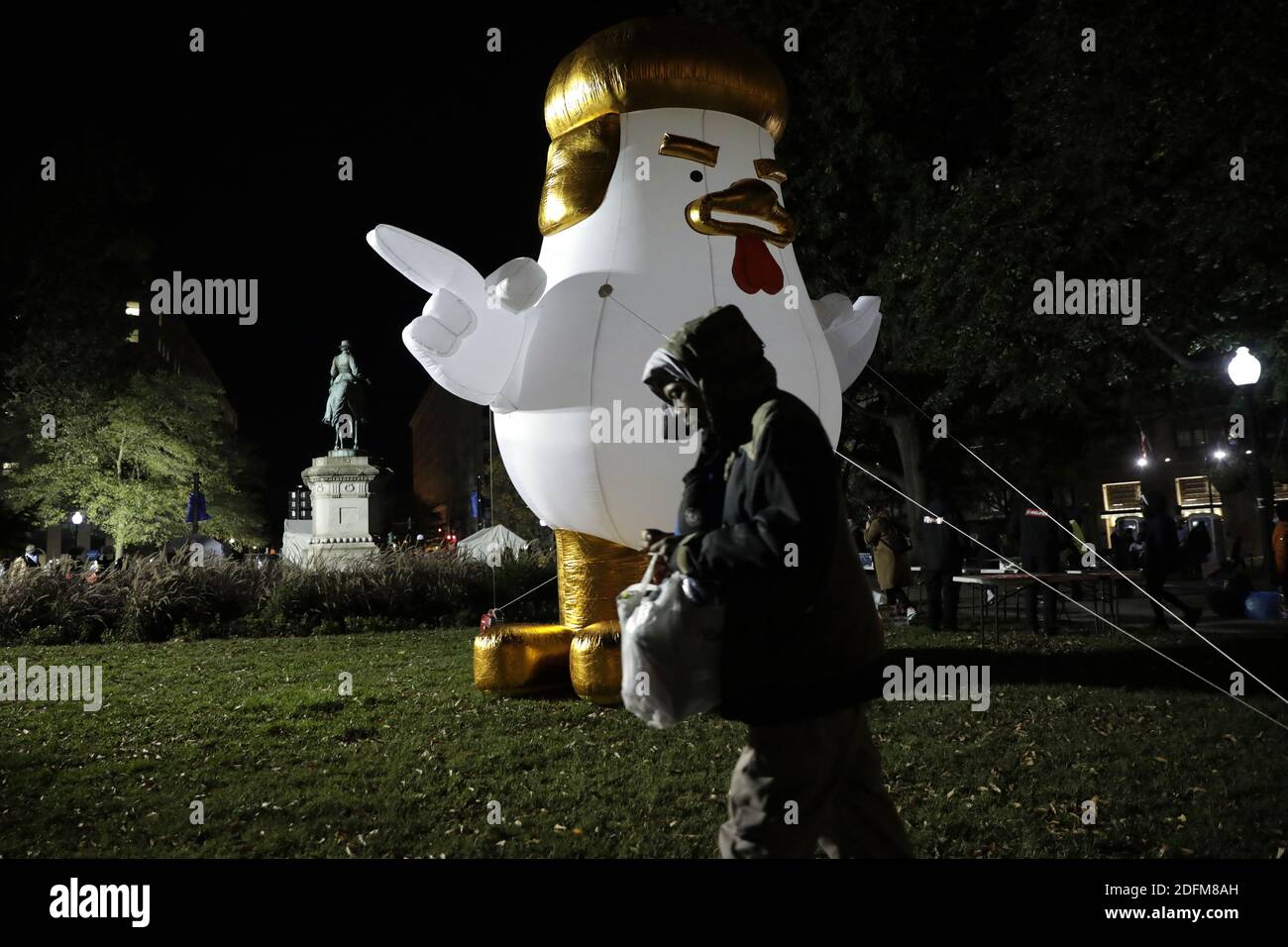 Ein Mann geht an einem riesigen aufblasbaren Huhn vorbei, das US-Präsident Donald Trump während der Präsidentschaftswahlnacht nahe dem Weißen Haus in Washington am 3. November 2020 beklagt. Foto von Yuri Gripas/ABACAPRESS.COM Stockfoto