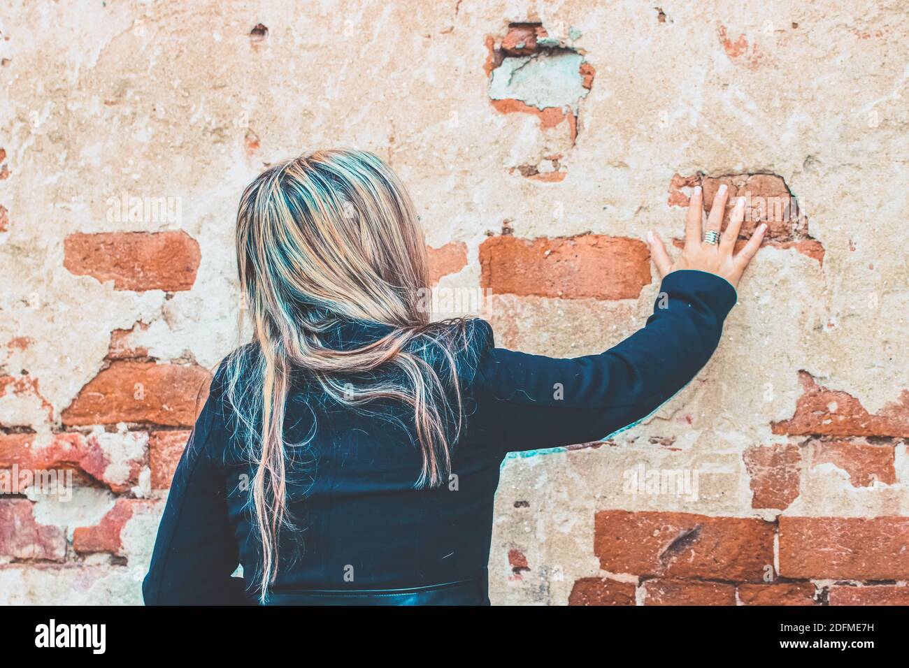 Blonde Frau vor der rustikalen Backsteinmauer Stockfoto