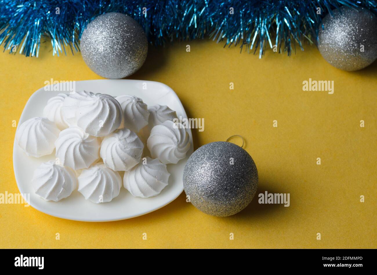 Mehrere Baseuren auf einem Teller auf einem strukturierten gelben Hintergrund mit Weihnachtsdekorationen. Selektiver Fokus. Stockfoto