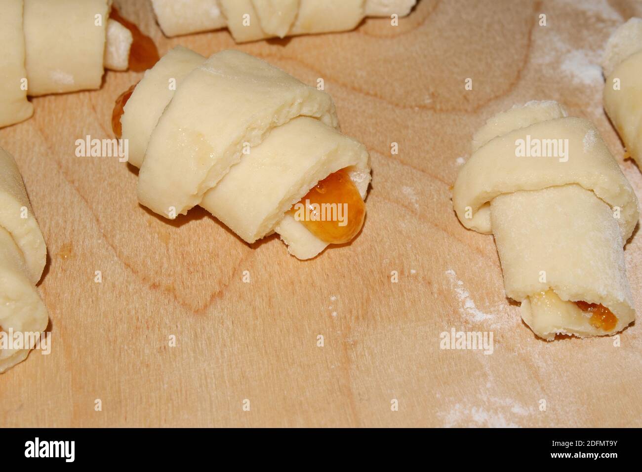 Kochen hausgemachte Brötchen mit Marmelade. Vorbereitet zum Backen von verdrehten Brötchen auf einem Holzbrett mit Mehl. Selektiver Fokus. Stockfoto