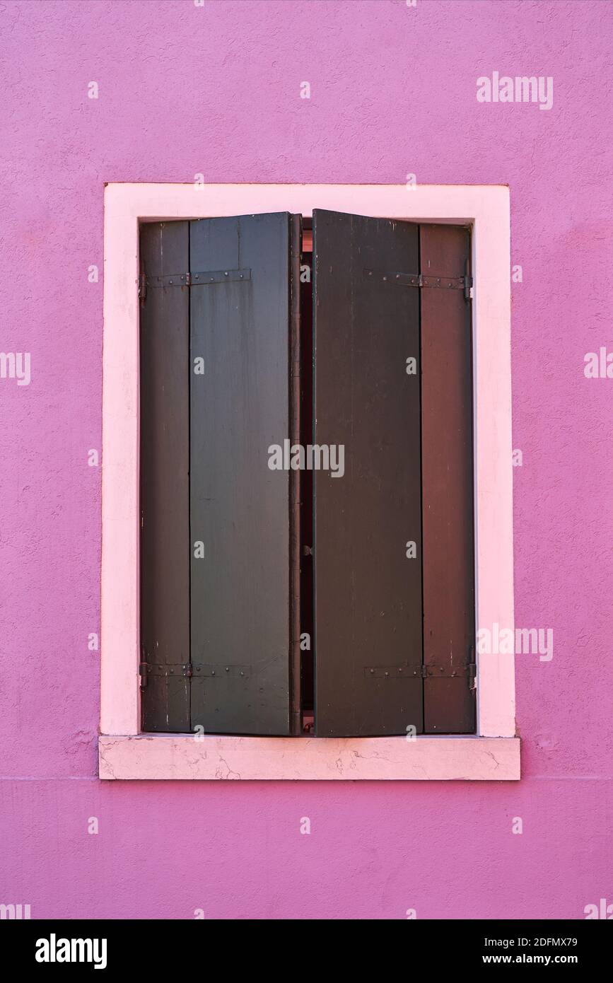 Fenster mit dem grünen Verschluss an der rosa Wand. Italien, Venedig, Insel Burano. Stockfoto
