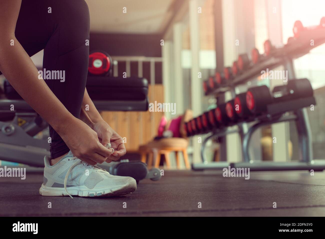 Nahaufnahme von Frauenhänden, die Schnürsenkel an Turnschuhen im Fitnessstudio binden. Stockfoto