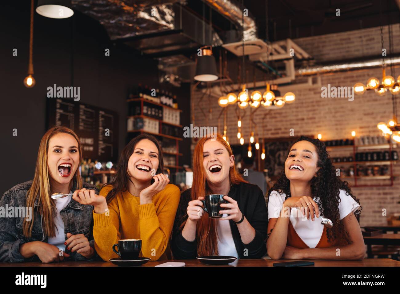 Fröhliche junge Frauen, die im Café sitzen. Freundinnen genießen ein Wochenende in einem Kaffeehaus. Stockfoto