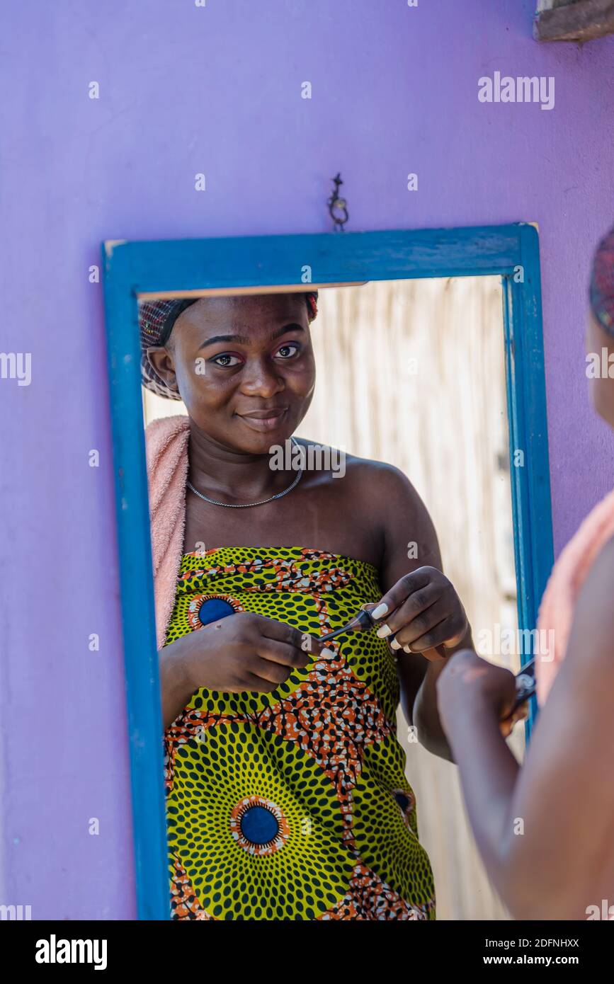 Afrikanische Frau tut ihr Make-up im Freien vor einem Spiegel im tropischen Teil von Ghana Westafrika Stockfoto