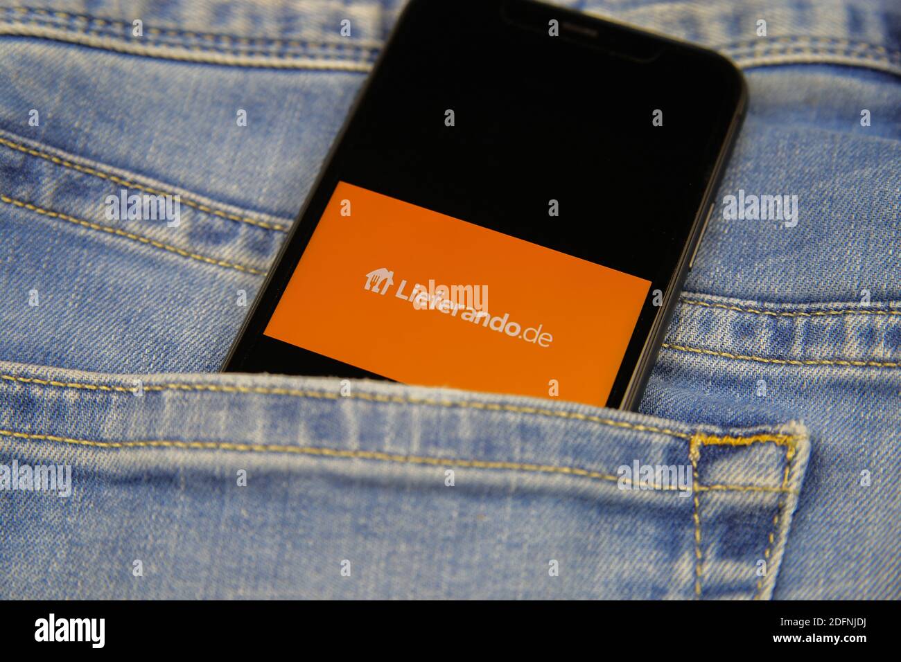 Viersen, Deutschland - 9. November. 2020: Nahaufnahme eines isolierten Mobiltelefons mit Lieferando-Logo-Schriftzug in Jeans-Tasche Stockfoto
