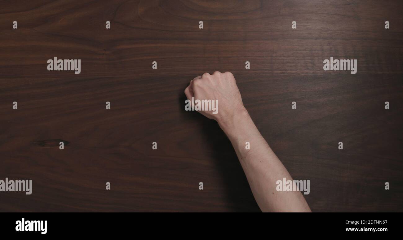 Draufsicht Mann Hand klopfen auf schwarzem Nussbaum Tisch mit Kopierraum, breites Foto Stockfoto