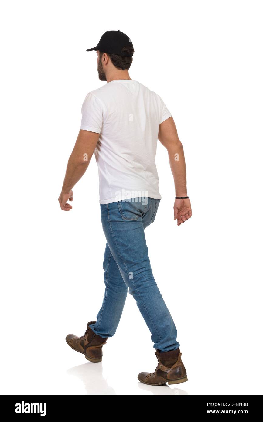 Wandermann mit Stiefeln, Jeans, weißem T-Shirt und schwarzer Mütze. Rückansicht. Studioaufnahme in voller Länge, isoliert auf Weiß. Stockfoto