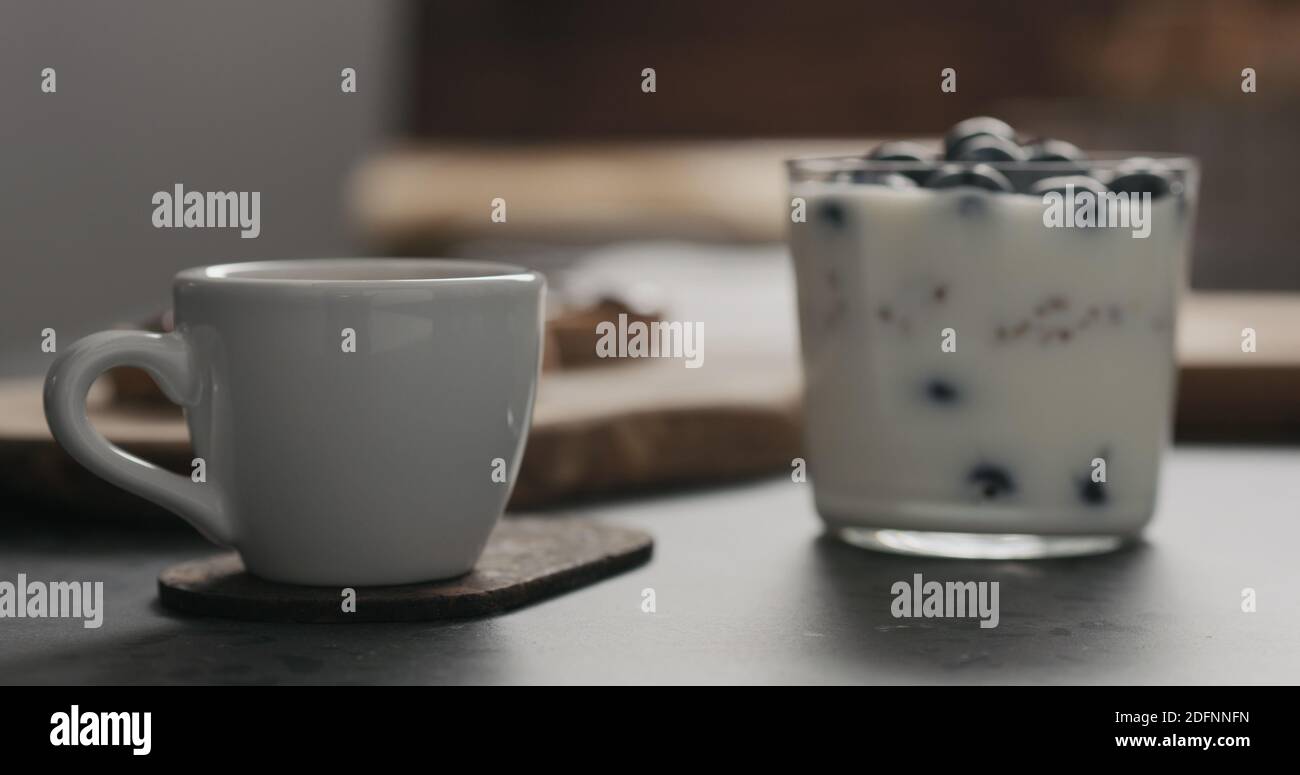 Espresso-Tasse neben Müsli mit Heidelbeeren im Glas mit Kopierraum, breites Foto Stockfoto