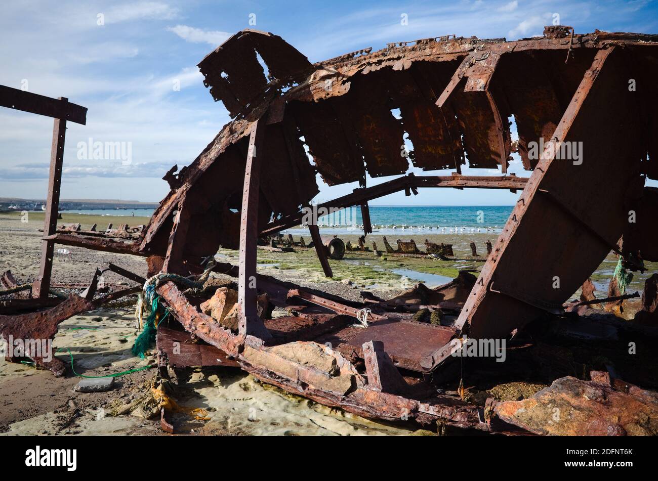 Altes verlassene rostige Boot liegt am Strand. Total beschädigte Metallschiff an der Meeresküste in der Nähe von Hafen in Puerto Madryn, Chubut, Argentinien Stockfoto