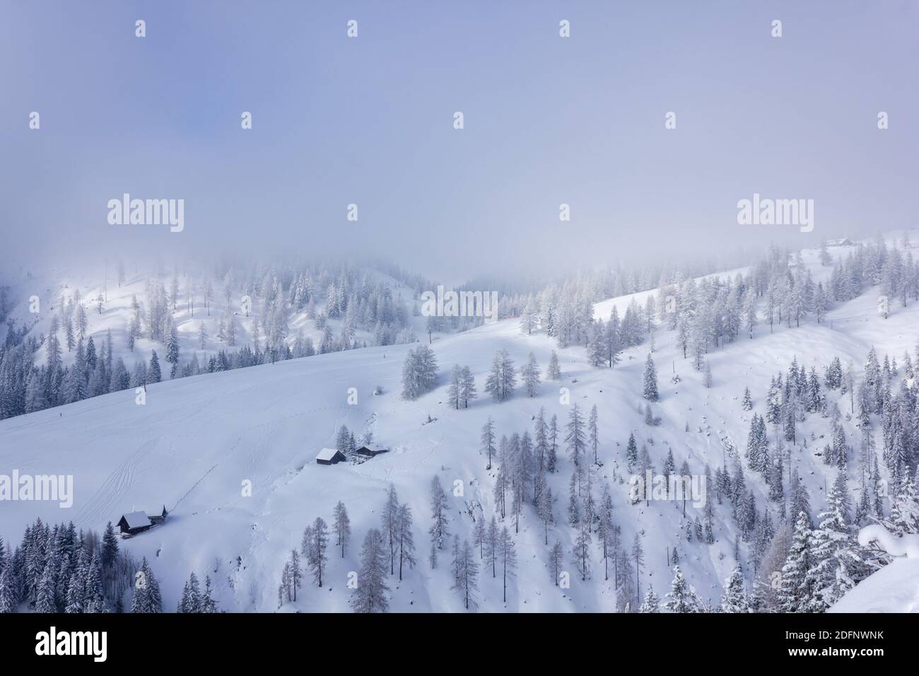 Ruhige Winterlandschaft in den österreichischen alpen mit Sonne, die durch den Nebel bricht (Ramsau am Dachstein, Liezen) Stockfoto