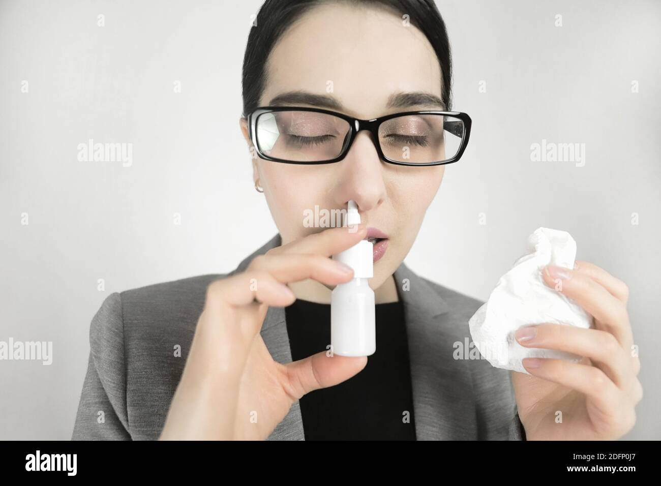 Junge Frau in Brille, verwendet Nasenspray. Stockfoto