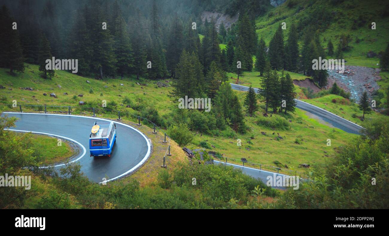 Alte Reisebuswagen auf einer Serpentinen Straße in der schweiz moody regnerischen Tag Stockfoto
