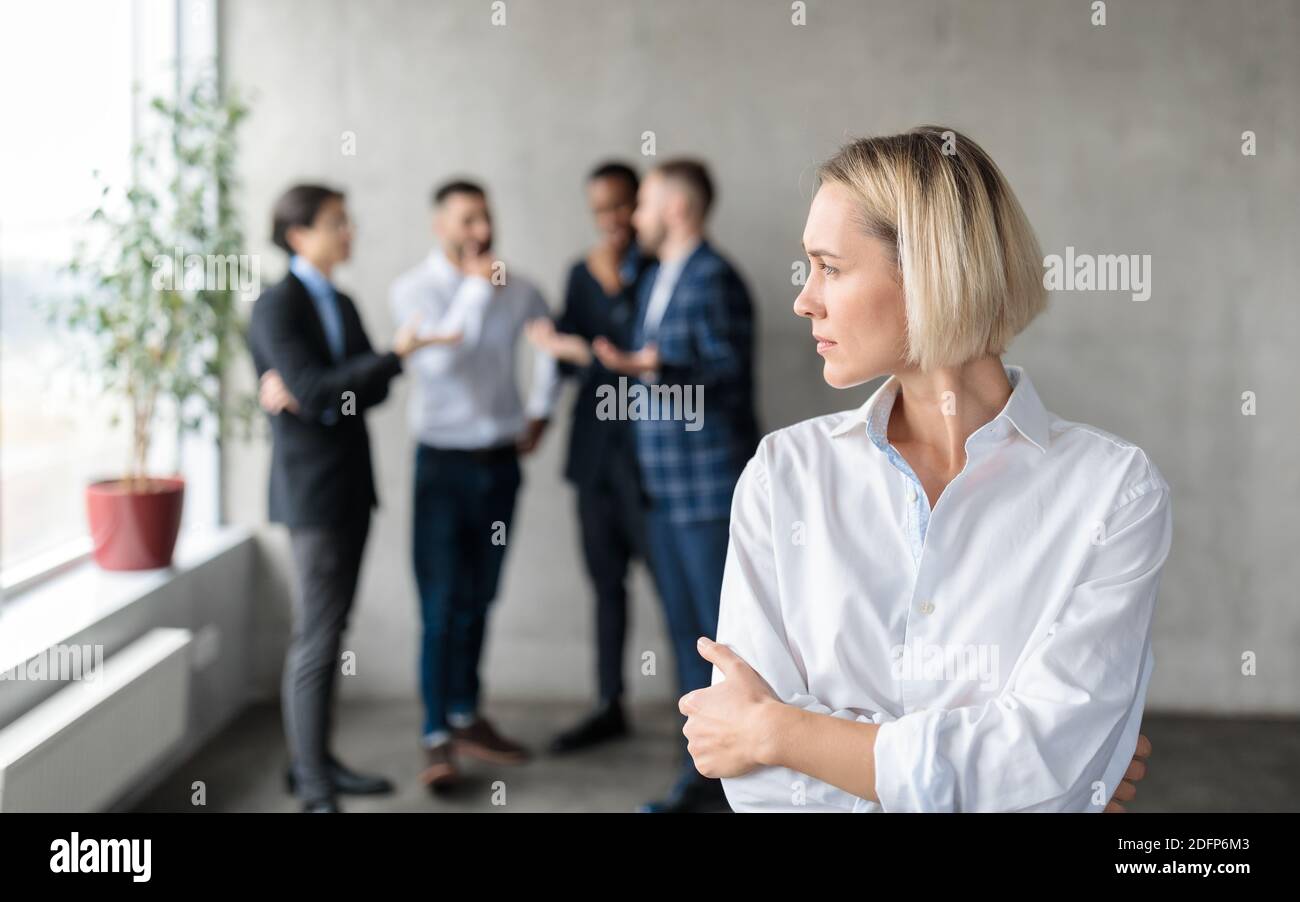 Männliche Mitarbeiter Flüstern Hinter Rücken Unglücklich Geschäftsfrau Im Büro Stockfoto