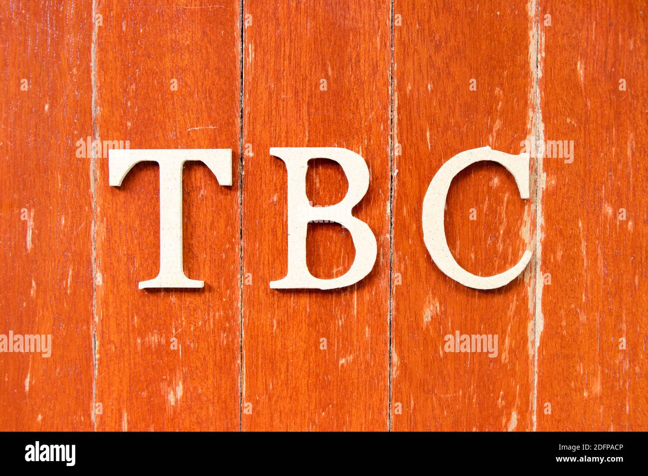 Buchstabe im Wort TBC (Abkürzung von muss bestätigt oder fortgesetzt werden) Auf alten roten Farbe Holzplatte Hintergrund Stockfoto