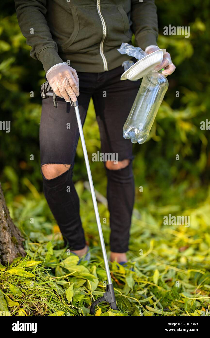 Männliche Freiwillige Abholung Plastikmüll aus Gras Stockfoto