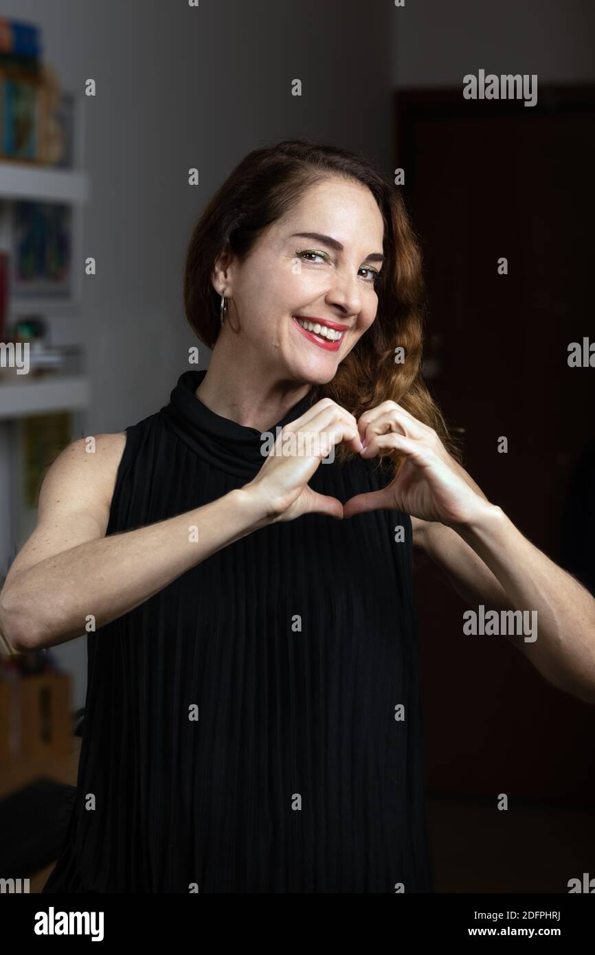 Glückliche Frau mittleren Alters mit toothy Lächeln machen die Form eines Herzens mit ihren Händen.. Stockfoto
