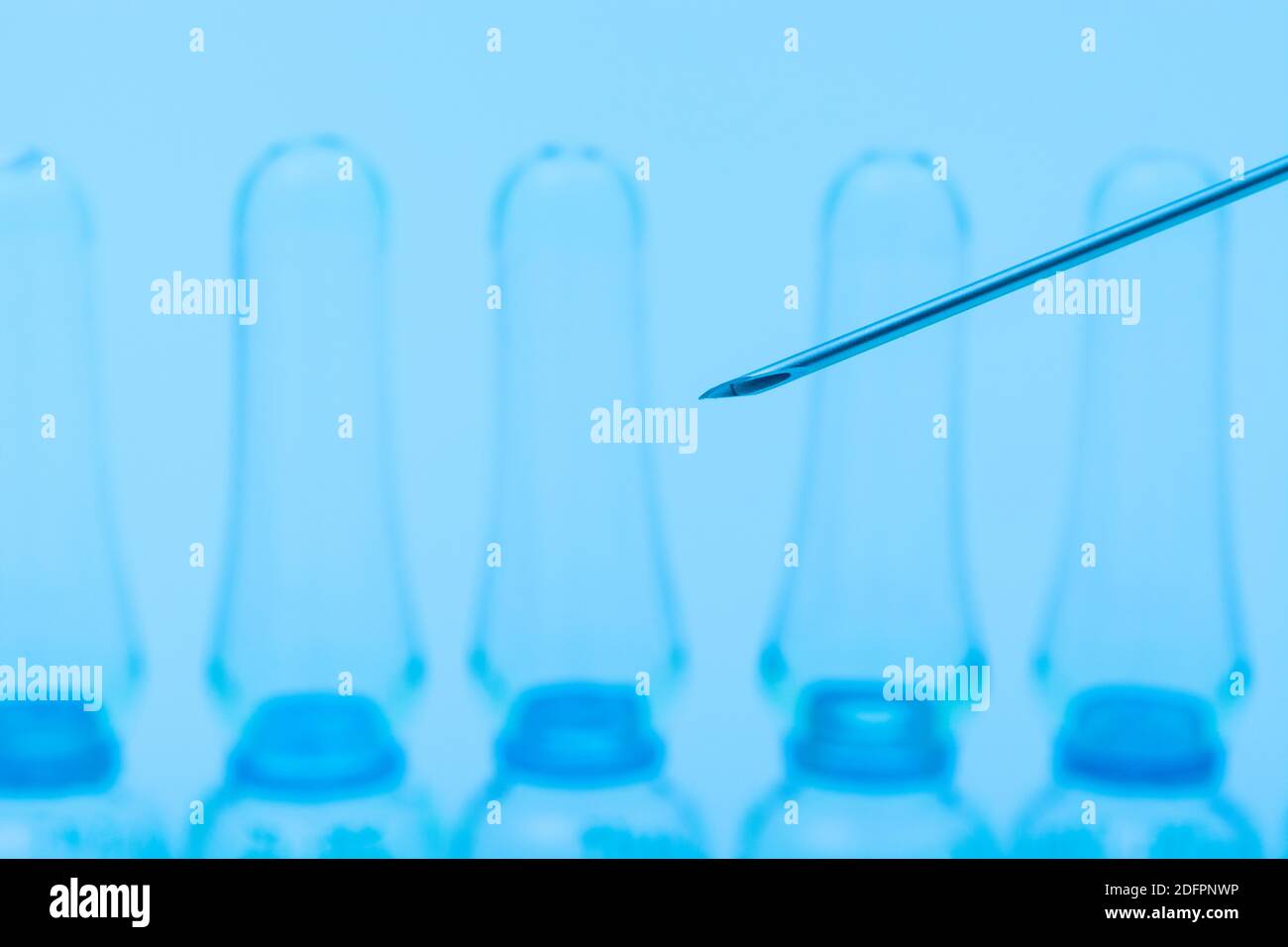 Verschwommene Glasampullen mit hypodermischer Spritze für Covid-Impfstoff, UK-Cunding Covid, V Day, Coronavirus-Impfstoff & scharfe Spritzenspitze auf neutralem B/Boden Stockfoto