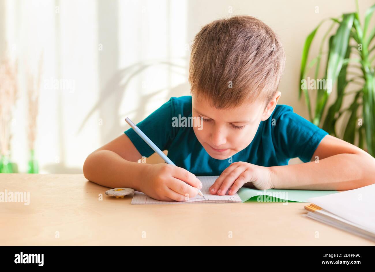7 Jahre alter Junge, der Mathematik macht, während er am Schreibtisch sitzt. Konzept der Heimschooling Stockfoto
