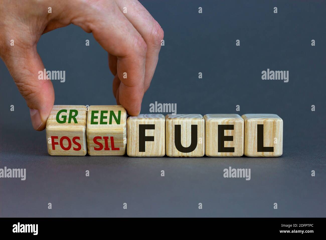 Vom fossilen zum grünen Brennstoff. Männliche Hand dreht Würfel und ändert die Wörter "fossile Brennstoffe" zu "grüner Brennstoff". Schöner grauer Hintergrund. Business und Green Fu Stockfoto