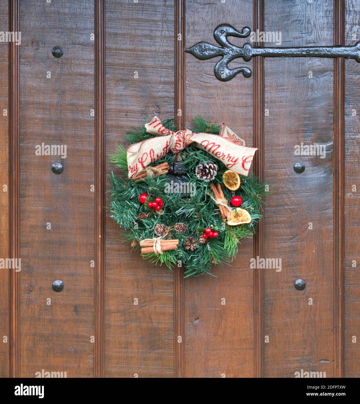 Ein hausgemachtes Weihnachtskranz auf einer Holztür mit schwarzen Armaturen. Stockfoto